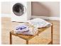Sacs à linge avec vêtements sur une étagère en bois, avec une machine à laver en arrière-plan.