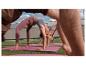 Trois personnes faisant du yoga sur des tapis roses sur l'herbe, en leggings et hauts de sport.