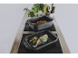 Deux plats à rôtir noirs avec du poisson et des légumes sur une plaque à induction