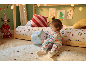 Un tout-petit joue avec une peluche dans une chambre d'enfant décorée pour Noël.
