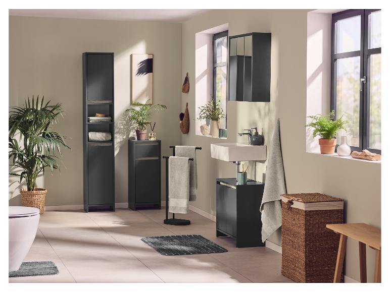 Salle de bain avec meubles noirs, lavabo, toilettes, plantes et textiles.