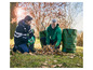 Deux hommes remplissent des sacs de jardin verts avec des feuilles.
