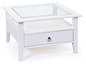 Table basse blanche avec plateau en verre et tiroir.