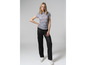 Une femme porte un chemisier gris clair à imprimé léopard et un pantalon noir.