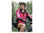 Femme en veste de cyclisme rose et casque noir sur un VTT.