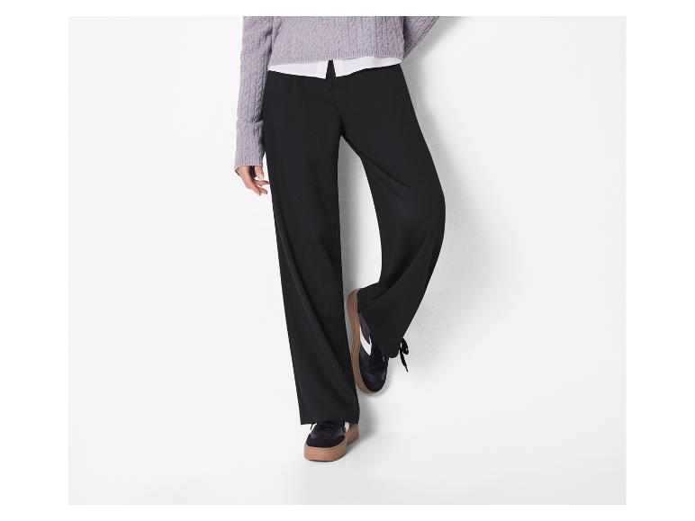 Pantalon noir large et pull violet clair avec une chemise blanche en dessous.