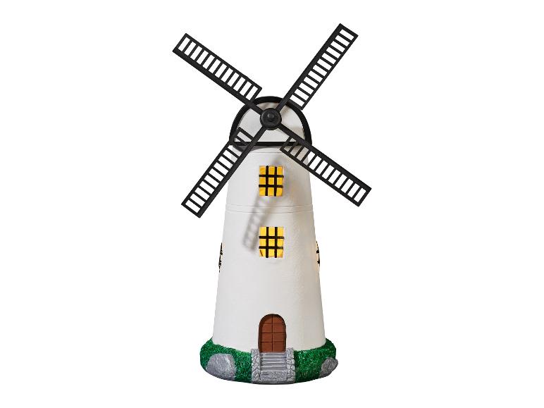 Un moulin à vent blanc avec des pales noires et des lumières