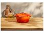 Cocotte Le Creuset orange sur un plan de travail en bois.