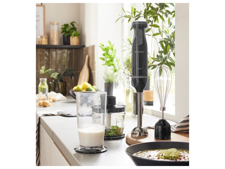 Un mixeur plongeant Silvercrest noir avec plusieurs accessoires dans une cuisine.