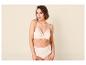 Femme souriante en soutien-gorge et culotte couleur crème avec de la dentelle.