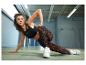 Femme en brassière de sport noire et leggings imprimés, faisant de l'exercice.