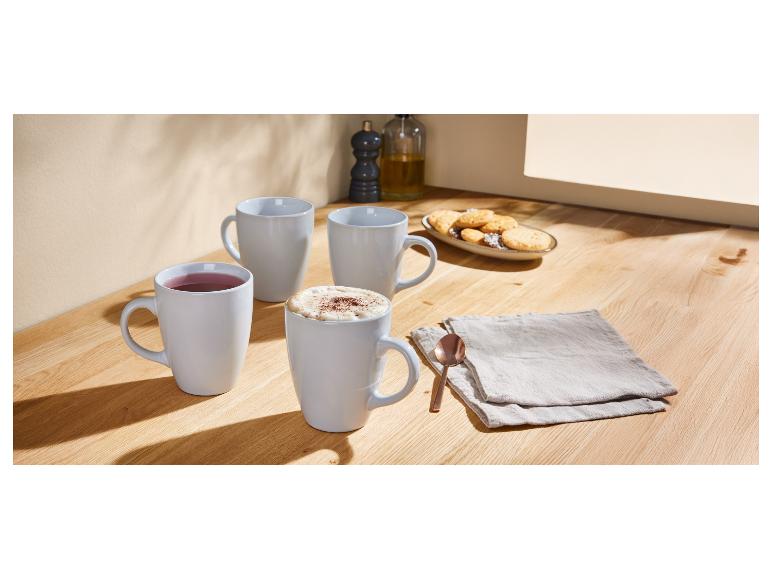 Trois mugs à café et des biscuits sur une table en bois.