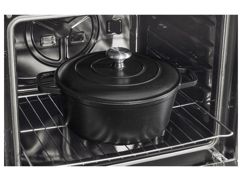 Marmite noire en fonte avec couvercle à l'intérieur d'un four sur une grille métallique