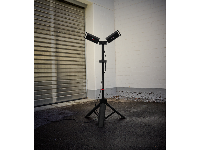 Éclairage de travail avec deux projecteurs sur trépied devant une porte de garage.