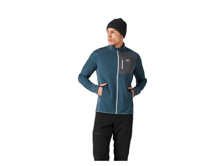 Homme en veste polaire sarcelle et grise avec un pantalon noir et un bonnet foncé.