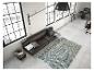 Un canapé en cuir noir avec un tapis gris dans un intérieur moderne.