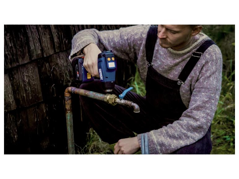 Homme utilisant un pistolet thermique sans fil 18 V pour travailler sur un tuyau extérieur.