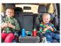 Deux enfants en sièges auto avec un repose-gobelets et des boissons.