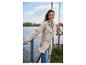 Femme en veste de pluie beige et jean, souriante au bord d'un lac.