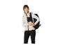 Femme en gilet polaire crème et pantalon noir, portant un sac à dos noir.