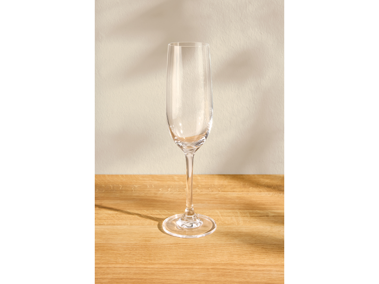 Flûte à champagne vide sur une surface en bois avec un fond clair.