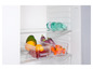 Un réfrigérateur avec de l'eau minérale de la marque Saskiabrand, des oranges, des baies rouges, des aubergines et des poivrons.