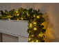 Guirlande de Noël avec lumières LED blanc chaud drapée sur une cheminée blanche.