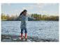 Enfant en imperméable et bottes jouant près de l'eau.