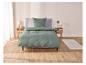 Une housse de couette verte sur un lit avec deux tables de chevet.