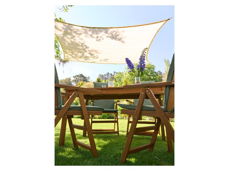 Ensemble repas extérieur avec table et chaises en bois, coussins verts, sous une voile d'ombrage.