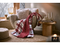 Fauteuil confortable avec un plaid à carreaux doux et un coussin décoratif.