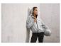 Une femme dans un sweat à capuche gris Crivit et un legging noir tenant un ballon de fitness.