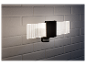 Un applique murale moderne noir avec détecteur de mouvement et éclairage LED, monté sur un mur en briques blanches.