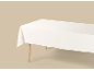 Nappe blanche sur une table en bois sur fond beige.