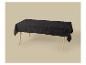 Une nappe noire scintillante recouvre une table en bois sur un fond beige.