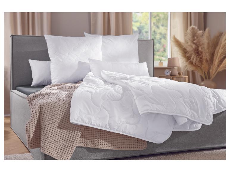 Lit avec cadre gris, literie blanche et couverture beige dans une chambre.