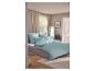 Chambre avec lit, parure de lit menthe, rideaux beiges et parquet en bois.