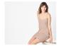 Jeune femme en robe à bretelles beige, assise sur un fond blanc.