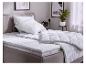 Lit avec couettes blanches, oreillers et surmatelas dans une chambre.