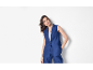Femme en gilet et pantalon bleu marine, posant avec une main dans la poche.