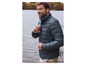 Homme en veste d'hiver vert foncé au bord de l'eau.