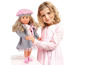 Une fille portant une robe rose tient une poupée avec un manteau gris.