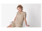 Modèle souriant portant un t-shirt et un short beiges.