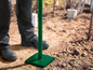 Un poteau vert avec une plaque de base est enfoncé dans le sol.