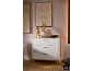 Commode blanche moderne à trois tiroirs avec plateau en bois dans une pièce chaleureuse.