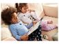 Deux enfants en pyjama Mickey Mouse lisant un livre sur le canapé.