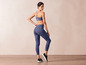 Un mannequin porte un soutien-gorge de sport bleu et des leggings avec un motif abstrait.