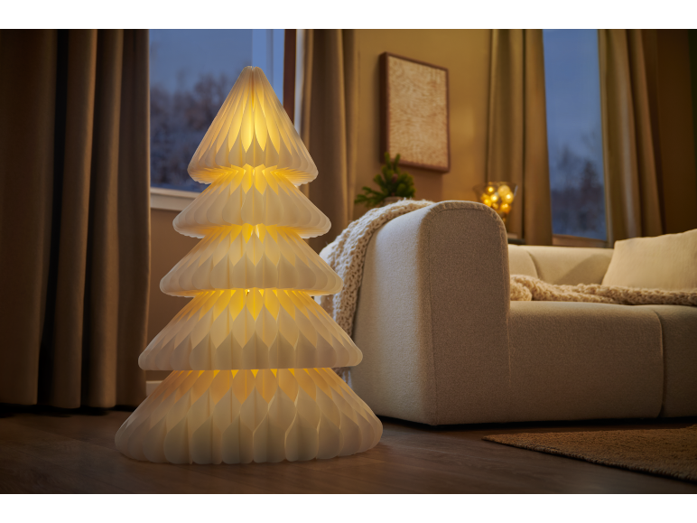 Lampadaire décoratif en forme de sapin de Noël lumineux dans un salon chaleureux.