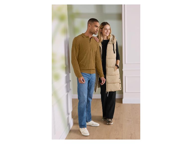 Homme en pull polo marron et jean, femme en longue veste beige et tenue noire.