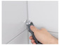 Une main utilise un outil pour nettoyer un joint dans une salle de bain carrelée.